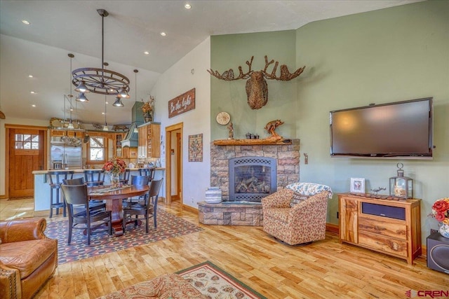 living room with high vaulted ceiling, a fireplace, baseboards, and wood finished floors