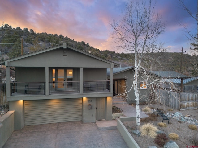 view of front of home featuring a balcony, an attached garage, concrete driveway, and stucco siding