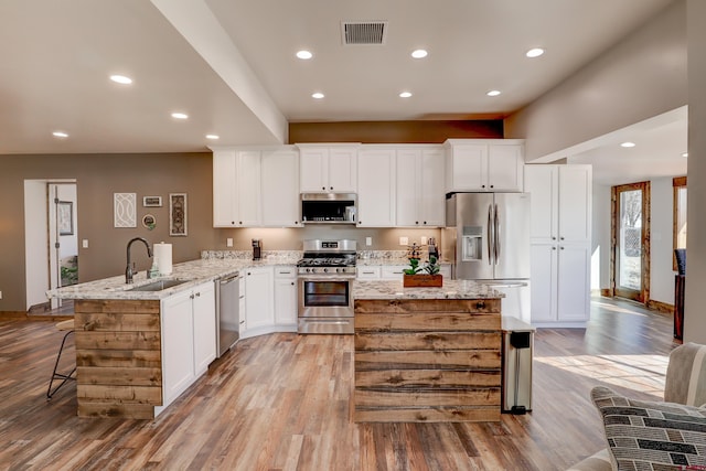 kitchen featuring stainless steel appliances, visible vents, white cabinetry, a sink, and a peninsula