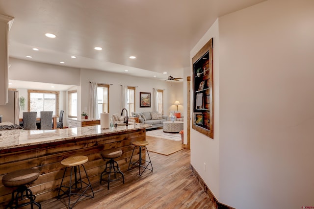 kitchen featuring light stone counters, a breakfast bar area, freestanding refrigerator, and light wood-style floors