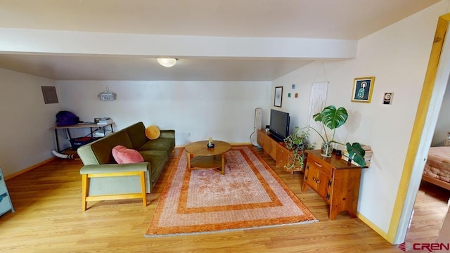 living room featuring wood finished floors, beam ceiling, and baseboards