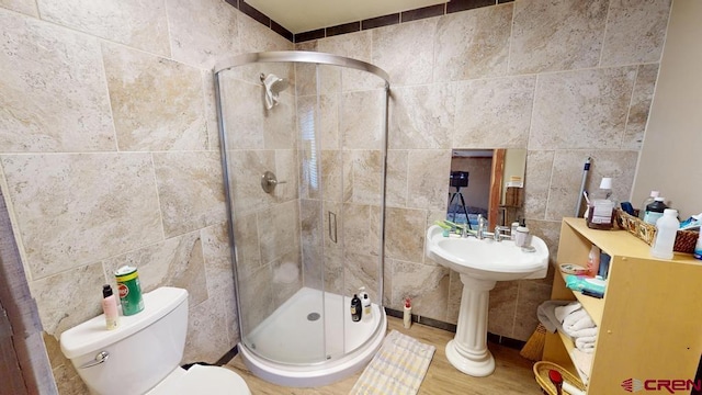 bathroom featuring toilet, a shower stall, tile walls, and wood finished floors