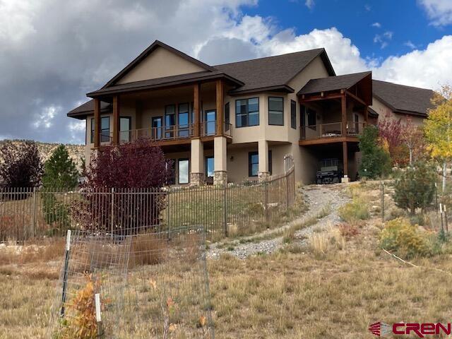 rear view of property with stucco siding and fence