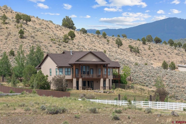 exterior space with stucco siding, fence, roof with shingles, and a mountain view