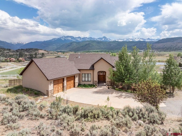 view of front of home featuring stucco siding, an attached garage, stone siding, and a mountain view