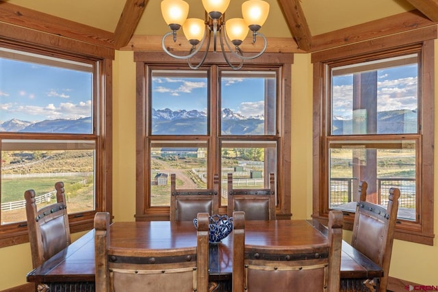 dining space with beamed ceiling, a mountain view, and a notable chandelier