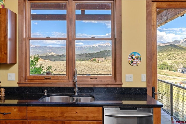 kitchen featuring brown cabinetry, a mountain view, a sink, and stainless steel dishwasher