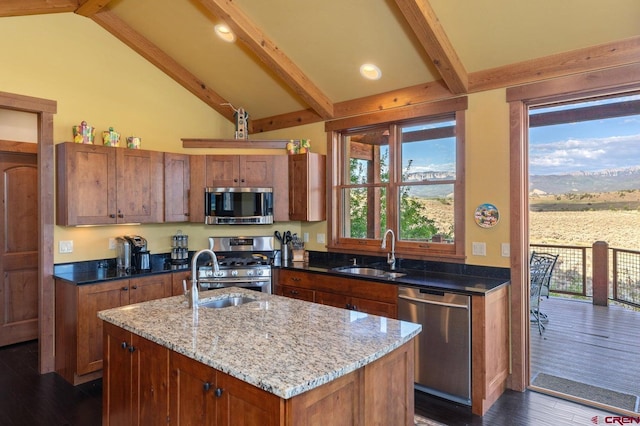 kitchen featuring a sink, light stone counters, beam ceiling, and appliances with stainless steel finishes