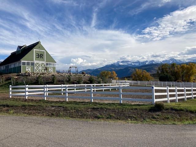 view of yard with fence, an enclosed area, a barn, a rural view, and a mountain view