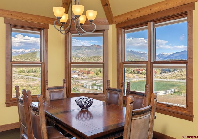 dining room featuring an inviting chandelier, baseboards, a mountain view, and beamed ceiling