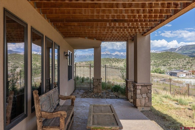 view of patio featuring a mountain view and fence