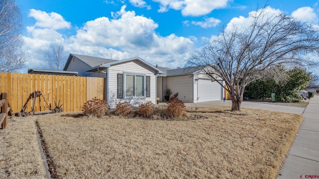 ranch-style house featuring a garage, driveway, and fence