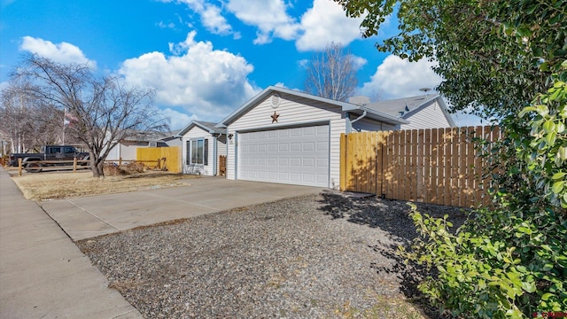 view of side of home with driveway, a garage, and fence