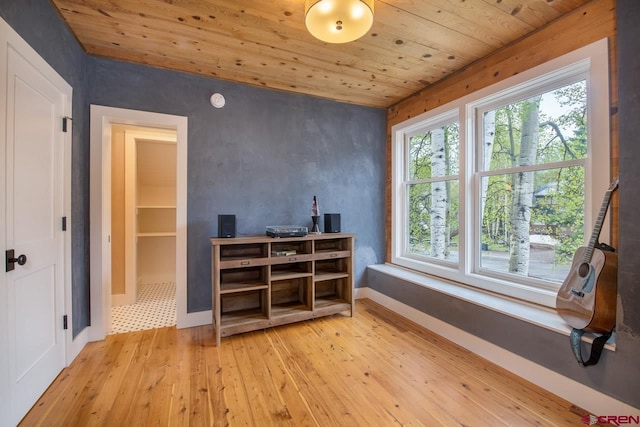 interior space with light wood-type flooring, wood ceiling, and baseboards