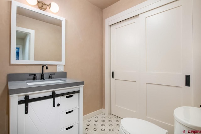 bathroom with toilet, baseboards, and vanity