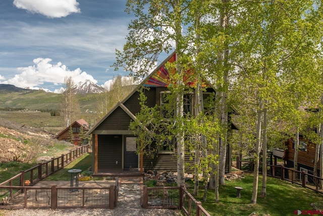 view of front of house with covered porch, a front lawn, fence private yard, and a mountain view