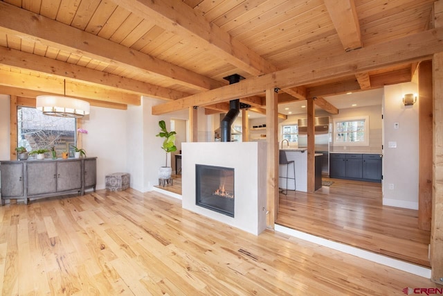 unfurnished living room with wood ceiling, a sink, wood finished floors, beamed ceiling, and baseboards