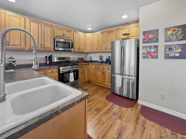 kitchen featuring appliances with stainless steel finishes, light wood-type flooring, dark countertops, and recessed lighting