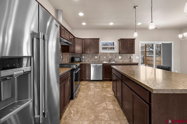 kitchen with stainless steel appliances, backsplash, a sink, dark brown cabinets, and under cabinet range hood