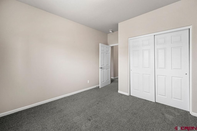 unfurnished bedroom featuring a closet, dark carpet, and baseboards