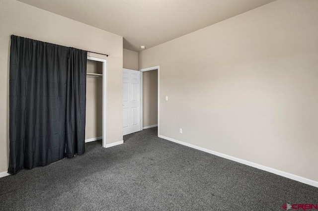 unfurnished bedroom featuring a closet, dark carpet, and baseboards