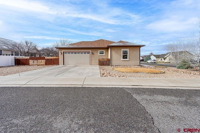 view of front of property with a garage, fence, concrete driveway, and stucco siding