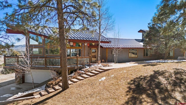 rear view of property featuring metal roof, a standing seam roof, and an attached garage