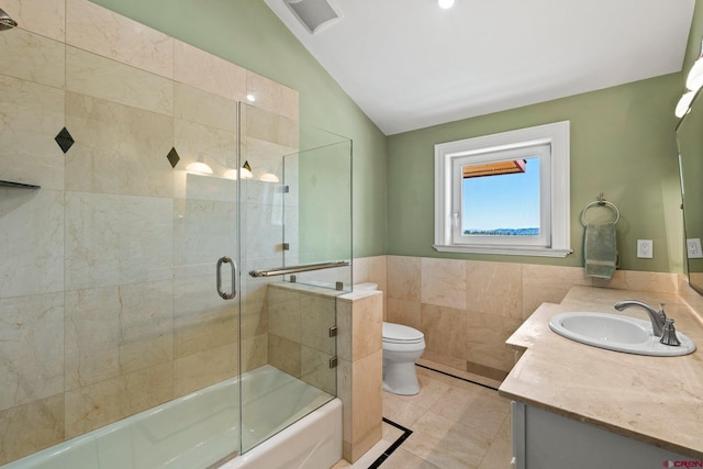 bathroom featuring tile patterned flooring, toilet, vanity, tile walls, and vaulted ceiling