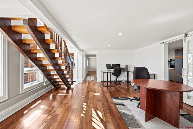 office area featuring hardwood / wood-style flooring, baseboards, and a barn door