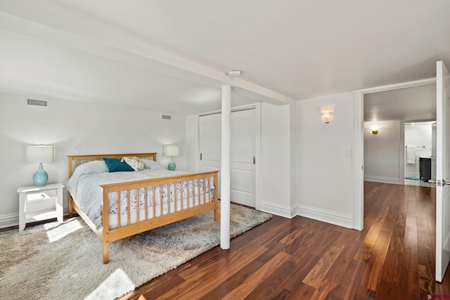 bedroom featuring two closets, wood finished floors, visible vents, and baseboards