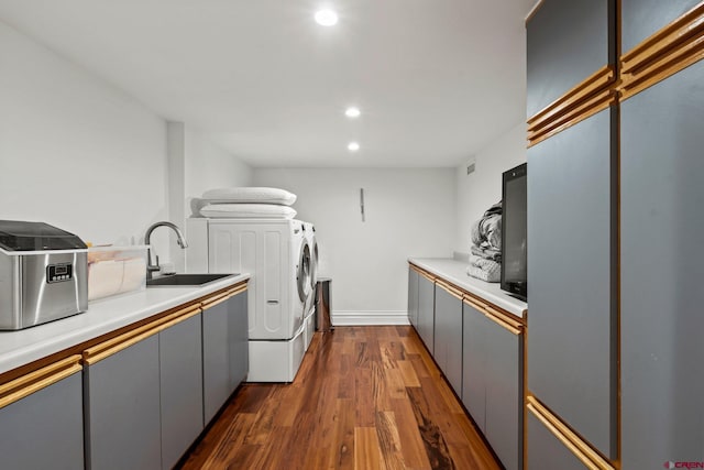 laundry area featuring cabinet space, washer and clothes dryer, dark wood-type flooring, a sink, and recessed lighting