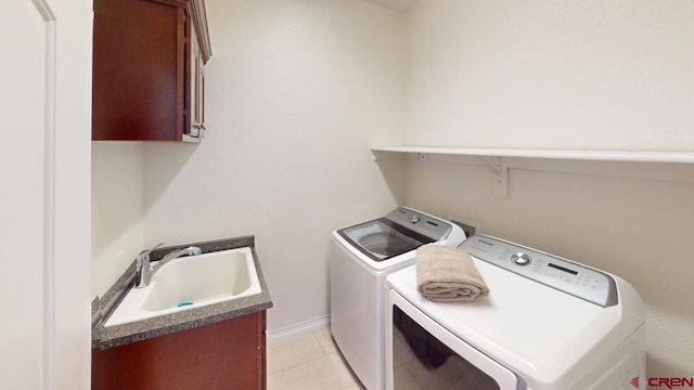 laundry room with cabinet space, baseboards, separate washer and dryer, a sink, and light tile patterned flooring