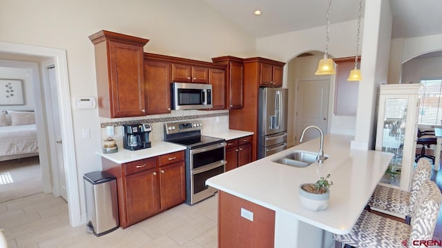 kitchen featuring vaulted ceiling, arched walkways, stainless steel appliances, and a sink