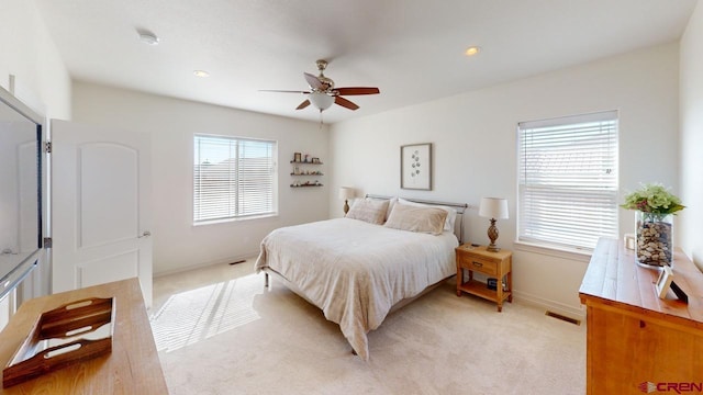 bedroom featuring baseboards, multiple windows, visible vents, and light colored carpet