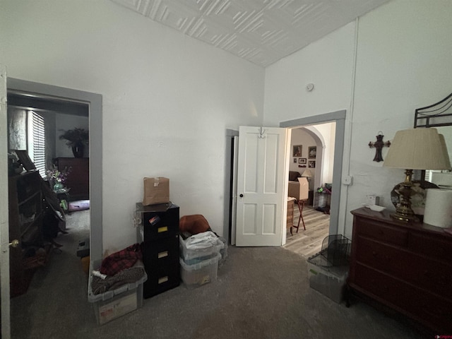 bedroom with carpet floors, arched walkways, and a towering ceiling