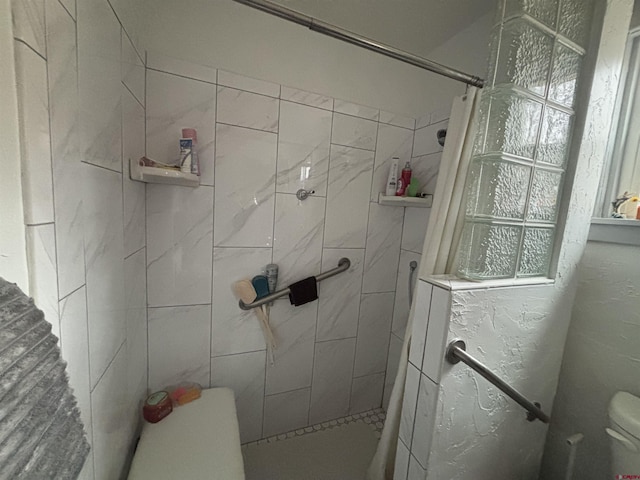 full bathroom featuring toilet and a tile shower