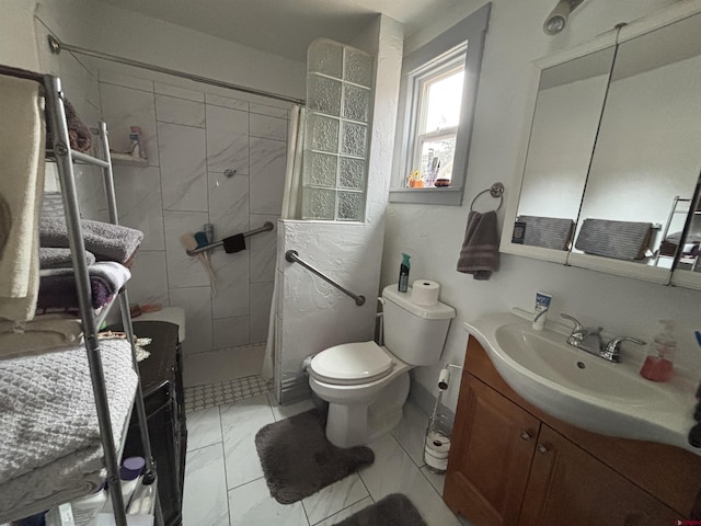 bathroom featuring marble finish floor, vanity, a tile shower, and toilet