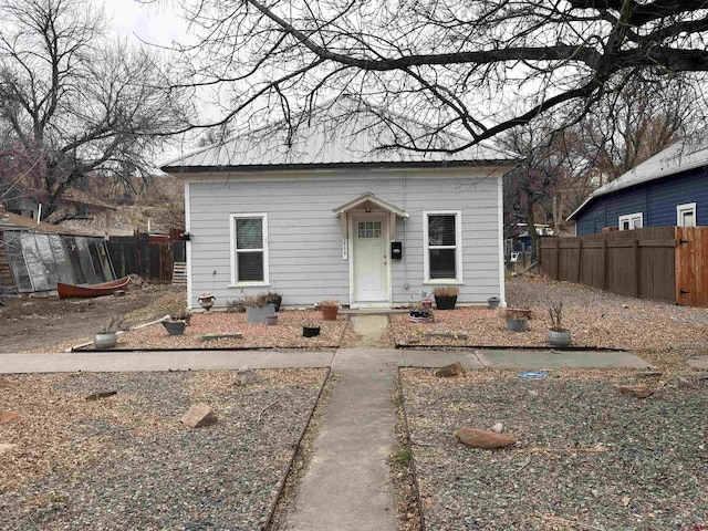 bungalow-style house with metal roof and fence