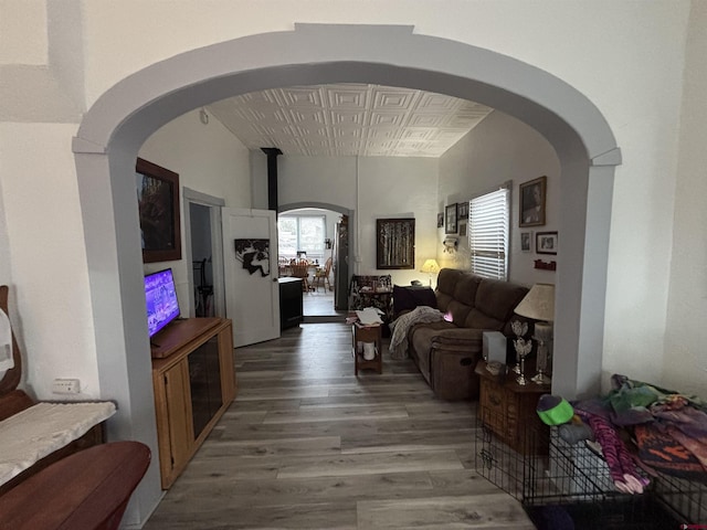 living area featuring an ornate ceiling, arched walkways, and wood finished floors