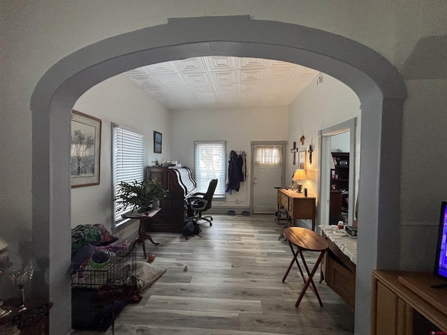 interior space with an ornate ceiling, arched walkways, and wood finished floors