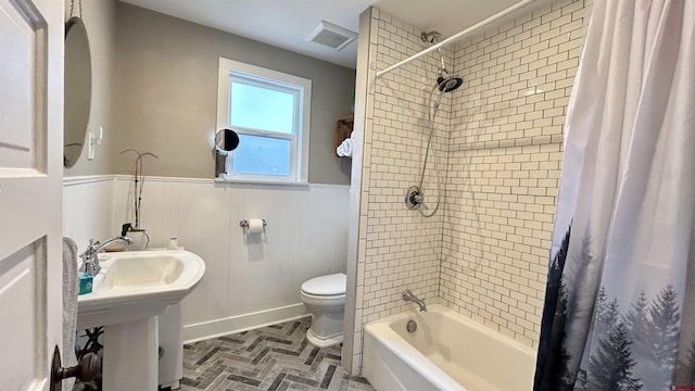 full bathroom with brick floor, visible vents, toilet, shower / bath combo, and wainscoting