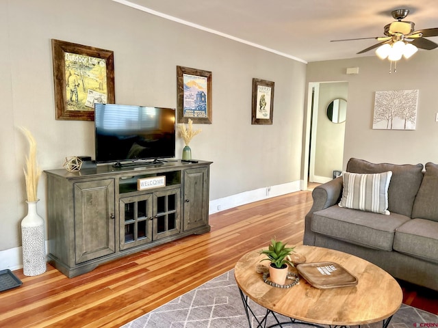 living room with ceiling fan, crown molding, light wood-style flooring, and baseboards