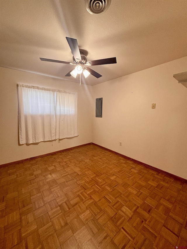 empty room featuring electric panel, baseboards, visible vents, a ceiling fan, and a textured ceiling