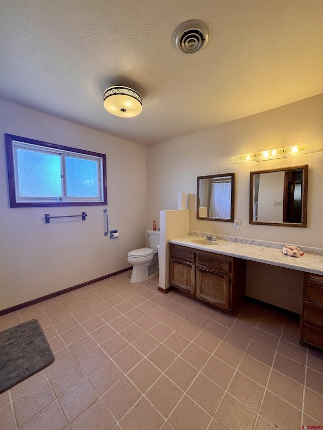 bathroom with toilet, vanity, baseboards, visible vents, and tile patterned floors