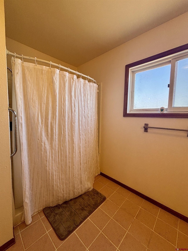 full bath featuring a shower with shower curtain, tile patterned flooring, and baseboards