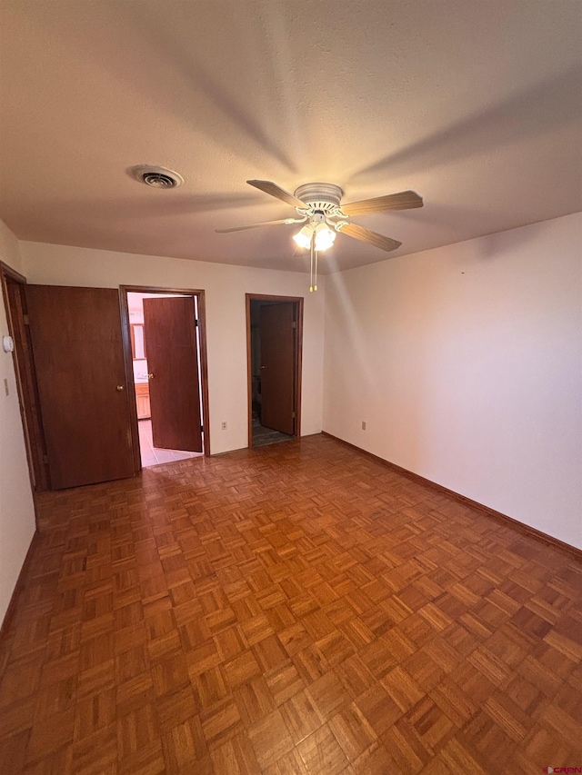 empty room featuring a ceiling fan, visible vents, a textured ceiling, and baseboards