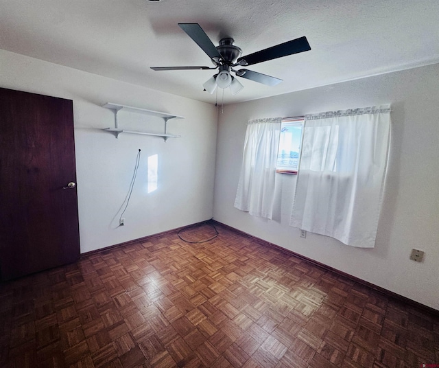 empty room with ceiling fan and baseboards