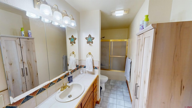 bathroom featuring combined bath / shower with glass door, vanity, toilet, and tile patterned floors