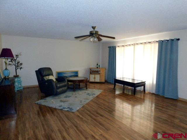 living area featuring a textured ceiling, a ceiling fan, and wood finished floors