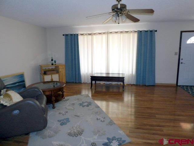 living area with wood finished floors and a ceiling fan